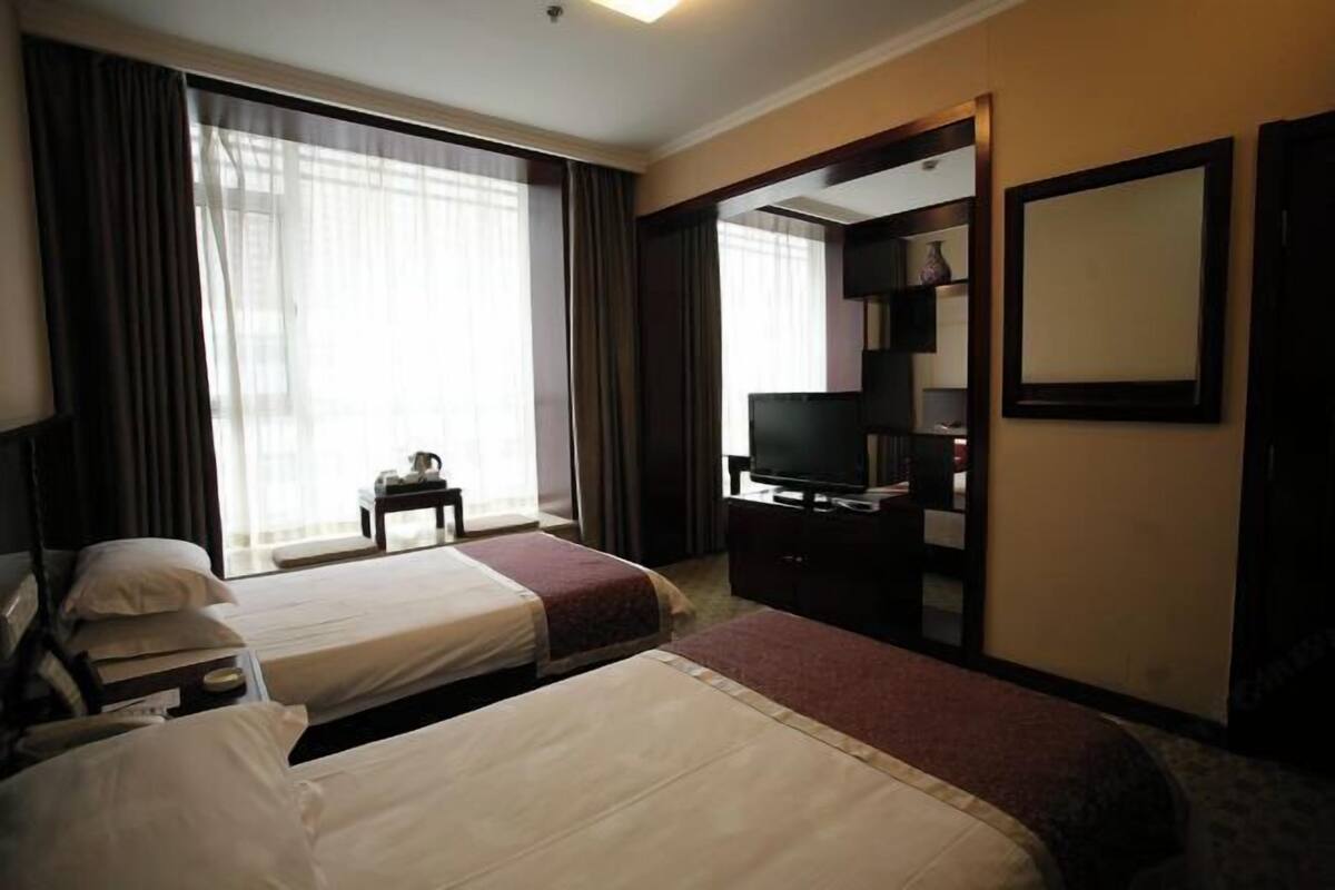 A hotel room with two beds, a television, a desk, and a wardrobe.