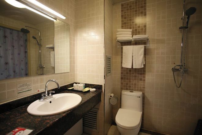 A bathroom with a sink, toilet, shower, and towel rack.