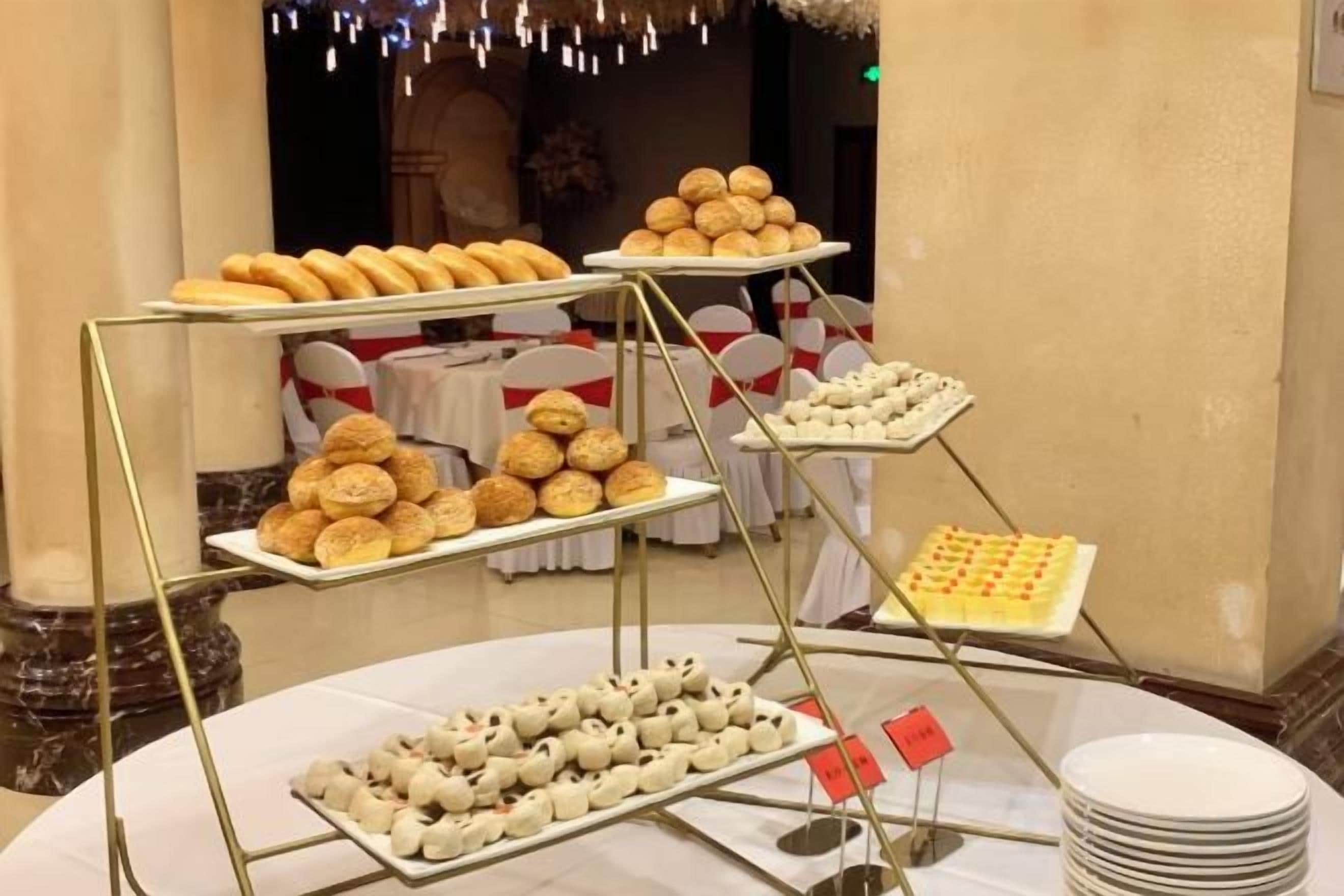 A buffet setup with multiple trays of pastries and desserts.