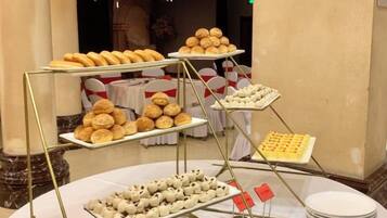 A buffet setup with multiple trays of pastries and desserts.