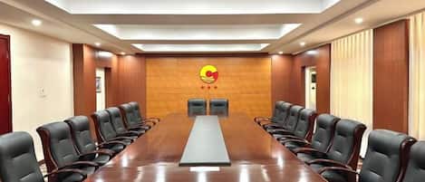 A conference room with a long table and chairs, a logo on the wall, and a modern ceiling design.
