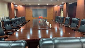 A conference room with a long table, multiple chairs, and a large screen.