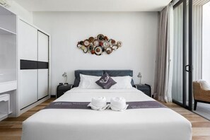 Quarto de hotel com uma cama, uma obra de arte na parede, uma mesa de cabeceira, uma cadeira e um guarda-roupa.