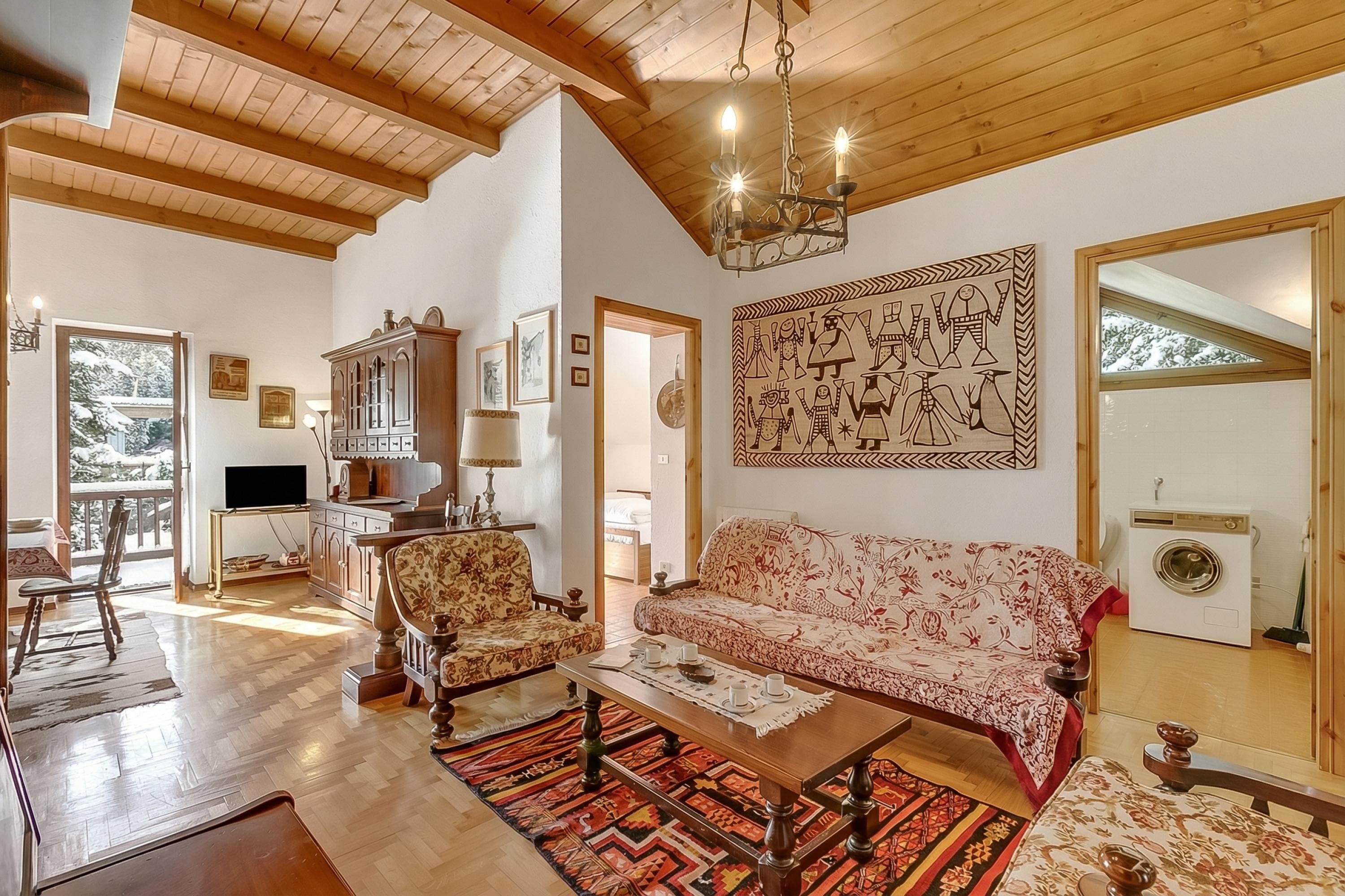 Un salon spacieux avec un plafond en bois, un canapé, une table basse et un téléviseur.