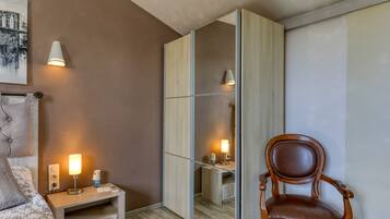 A bedroom with a bed, bedside table, lamp, chair, and a large mirror.