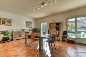 A spacious dining area with a large table, chairs, and a potted plant.