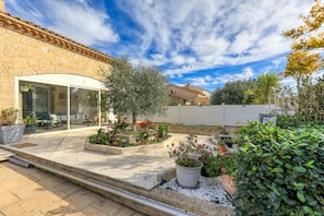 A stone building with a glass door, outdoor seating, and potted plants.