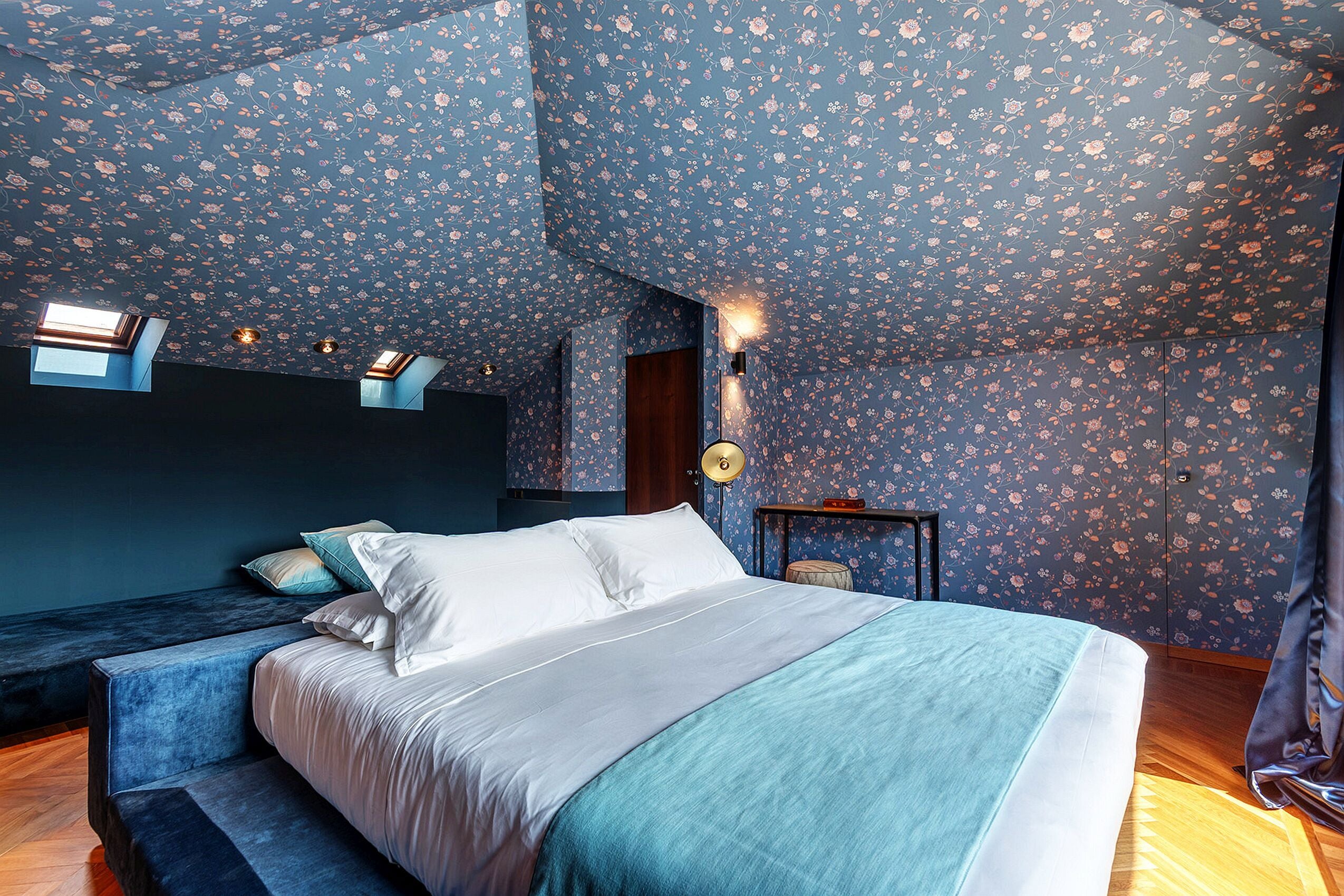 A bedroom with a bed, a bench, and a wall-mounted lamp.