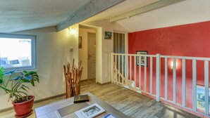 A room with a wooden floor, a red wall, a white railing, a potted plant, and a door leading to another room. - Villa Angelo - Lavande Guest Room with Shared Pool, Wi-Fi, and Air Conditioning (Saint-Thibéry)