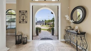 An entrance with a tiled floor, a decorative rug, a metal console table, and a view of a residential area.