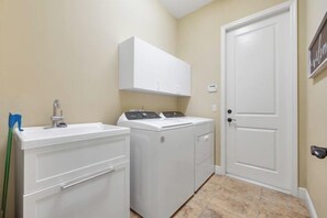 A laundry room with a washing machine, dryer, and a sink. - Villa Pearl (Cape Coral)