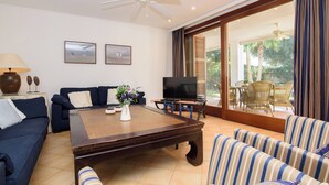 A living room with a sofa, striped armchairs, a coffee table, a TV, and a ceiling fan. - Samar Villa, centrally located, close to the beach, A/C, option of fenced pool (Santanyí)