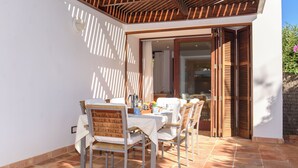 A patio with a table set for dining, surrounded by chairs, and a wooden pergola overhead. - Samar Villa, centrally located, close to the beach, A/C, option of fenced pool (Santanyí)