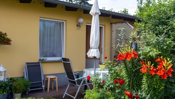 A yellow building with a patio area featuring a table, chairs, and an umbrella. - Holiday Home 'Stahlberg' with Private Terrace, Balcony and Wi-Fi (Potsdam)