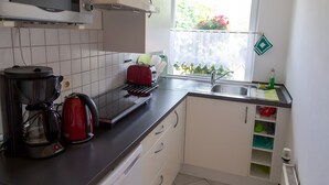 A compact kitchen with a microwave, coffee maker, toaster, and a window with a view of greenery. - Holiday Home 'Stahlberg' with Private Terrace, Balcony and Wi-Fi (Potsdam)