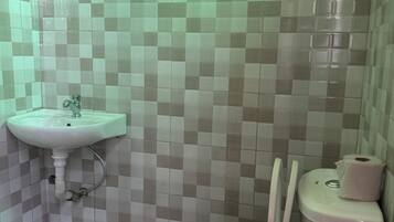 A bathroom with a toilet, a sink, and tiled walls.