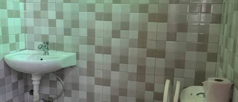 A bathroom with a toilet, a sink, and tiled walls.