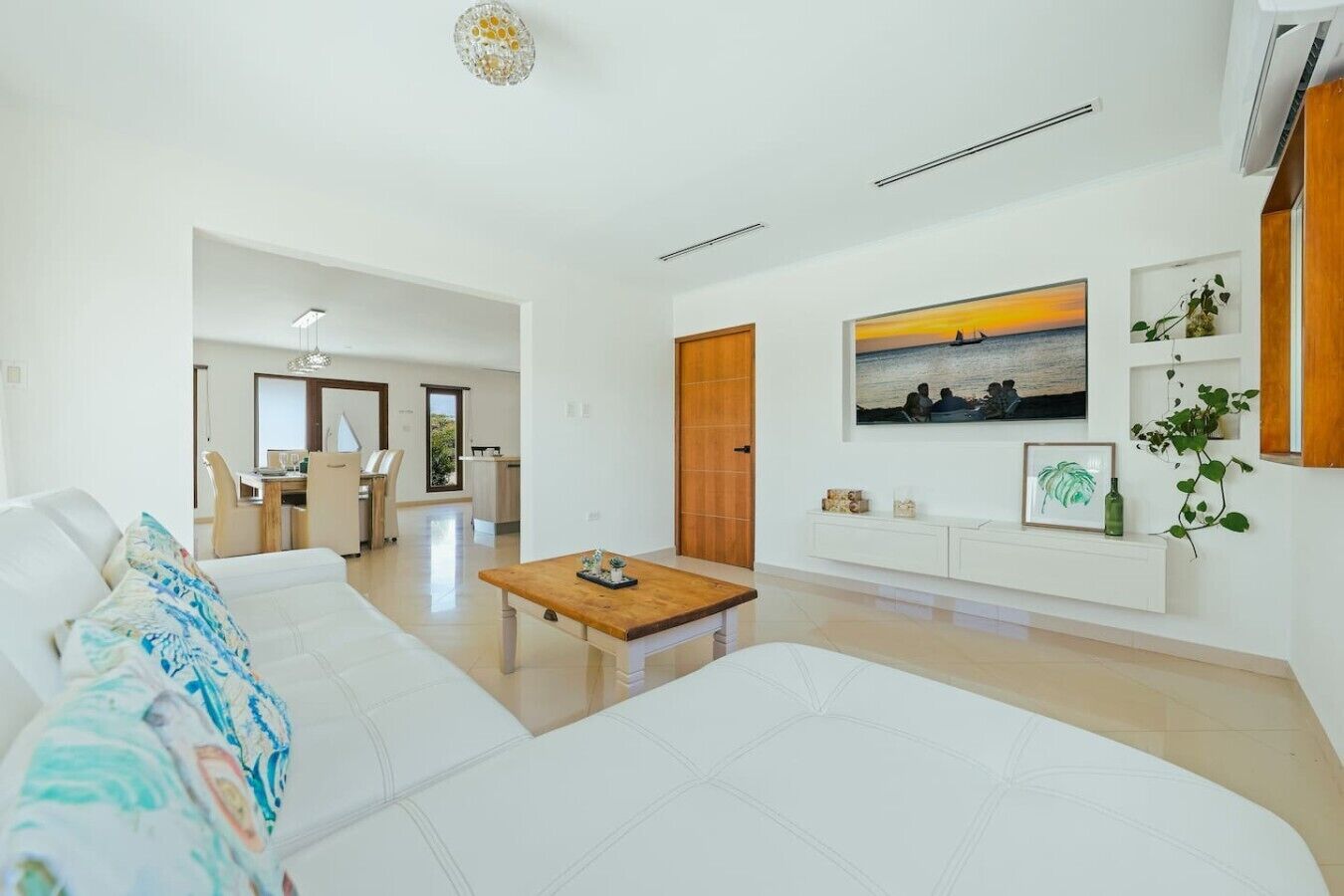 Una sala moderna con un sofá blanco, una mesa de centro de madera y un comedor al fondo.