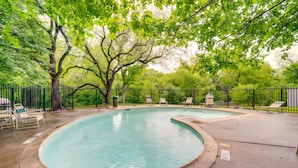 Una piscina a bordo curvo, circondata da una recinzione in metallo nero e alberi.