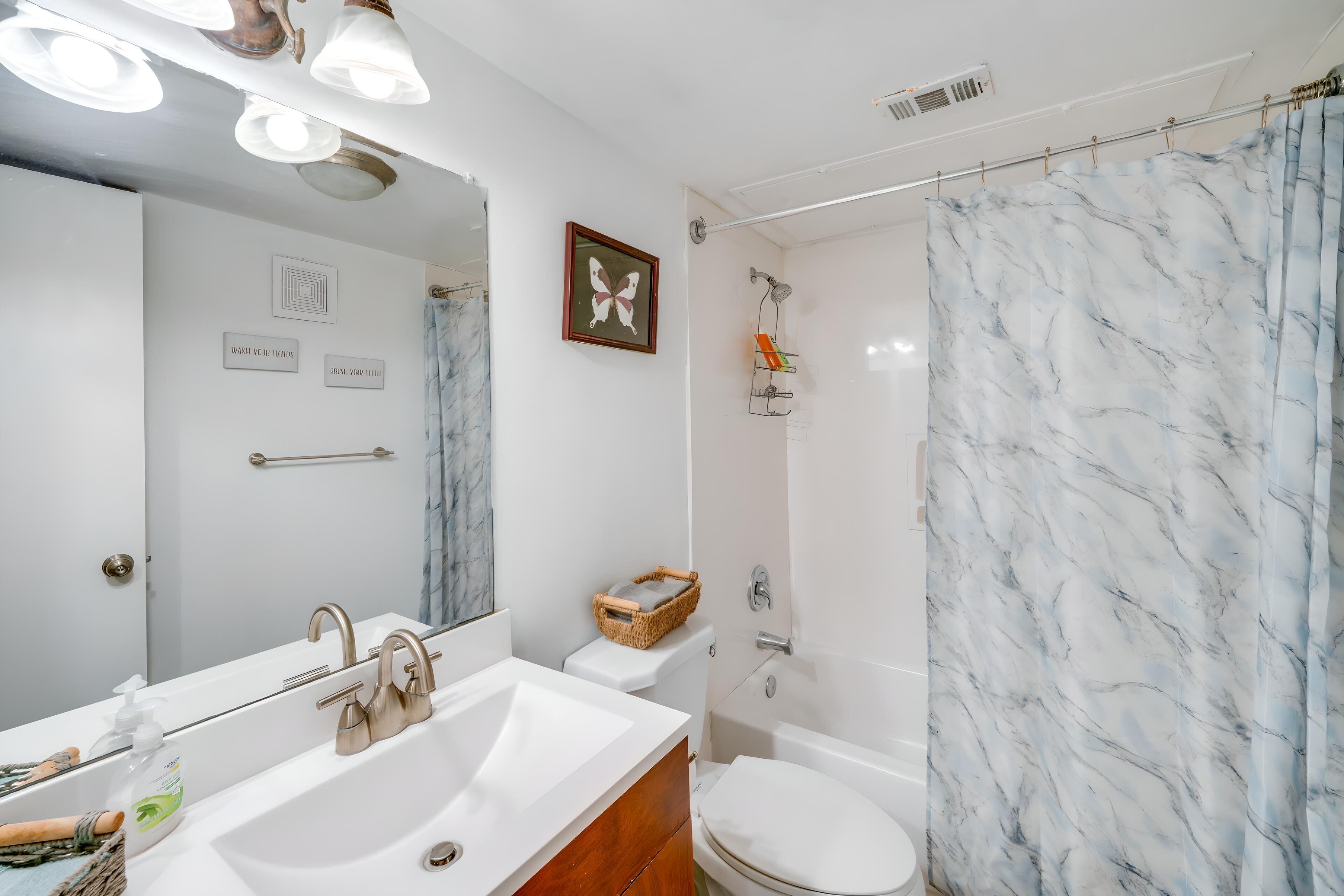 Une salle de bain avec un lavabo blanc, un miroir, des toilettes et un espace douche.