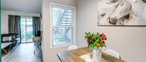 A dining area with a wooden table, a vase of flowers, and a large horse painting on the wall.