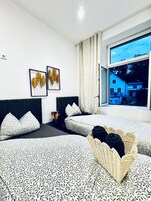 Ein Hotelzimmer mit zwei Betten, einem großen Fenster und Bildern an der Wand.