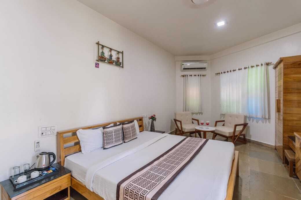 Habitació d'hotel amb llit, taula de nit i zona de seients petita amb cadires i taula.
