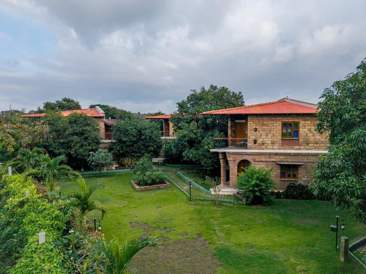 A traditional house with a red-tiled roof, surrounded by lush greenery and a well-maintained lawn.
