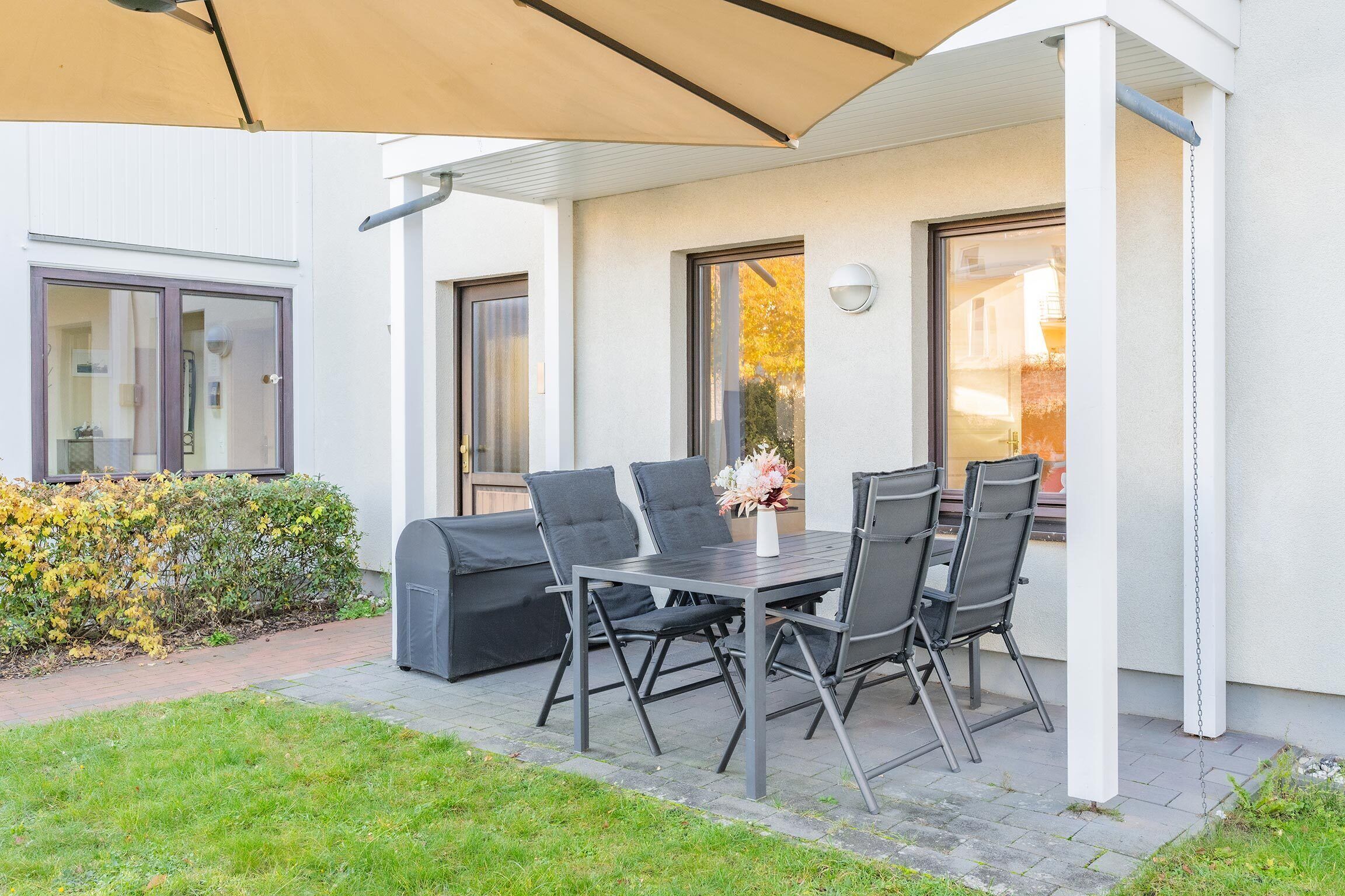 A patio with a table and chairs, a covered seating area, and a view of a building.