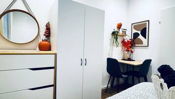 Un dormitorio moderno con cama, cómoda, escritorio y sillas.