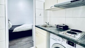 Een kleine keuken met een ingebouwde wasmachine, een spoelbak en een fornuis.