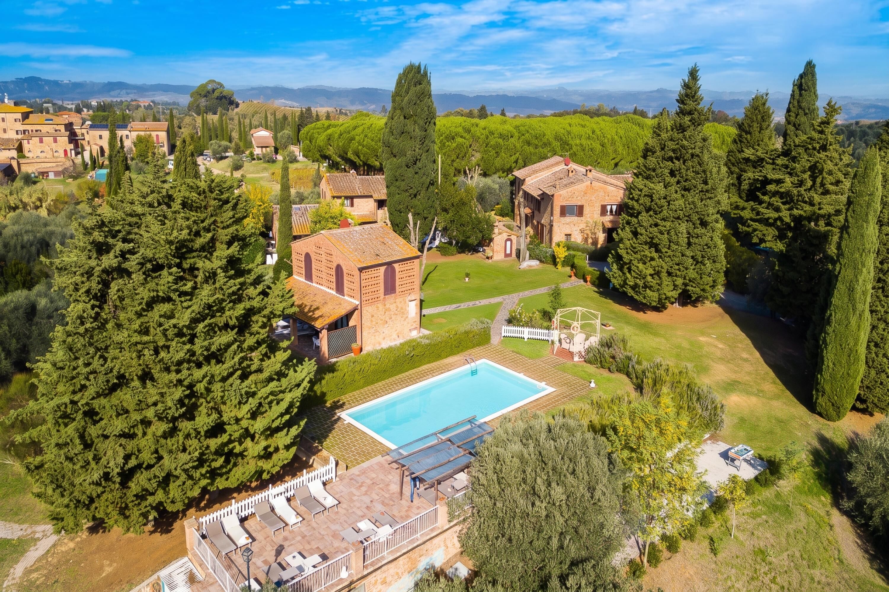 A residential property with a swimming pool, a patio with sun loungers, and a view of the surrounding landscape.