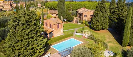A residential property with a swimming pool, a patio with sun loungers, and a view of the surrounding landscape.