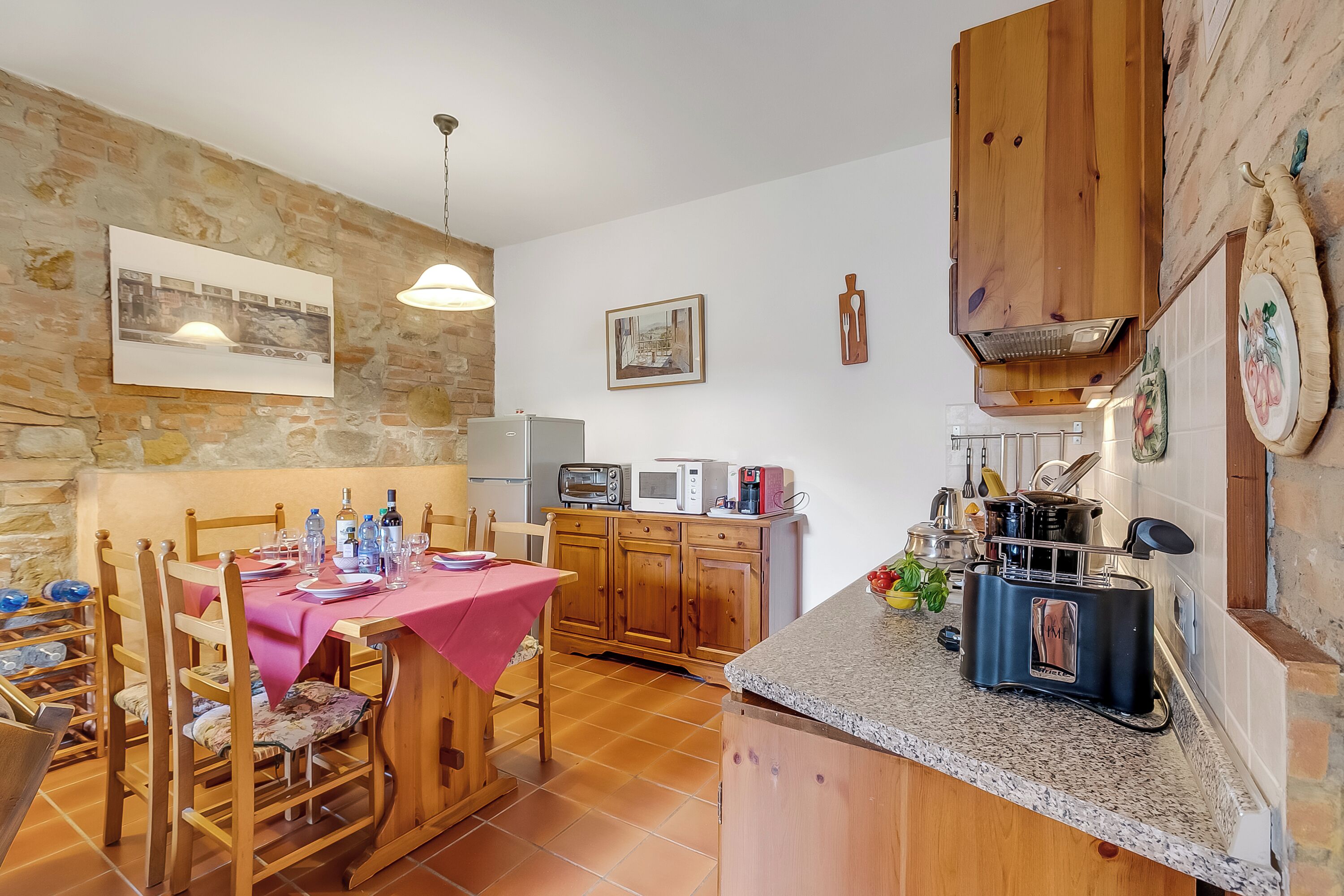 A kitchen with wooden cabinets, a dining table with chairs, and a countertop with a toaster.
