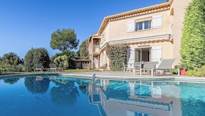 A swimming pool with lounge chairs and a building with a balcony. - Quiet House With Pool (Biot)