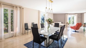 A modern dining area with a glass table, black chairs, and a vase of flowers. - Quiet House With Pool (Biot)