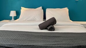 A hotel room with a bed, white linens, a dark blanket, two wall-mounted lights, and a nightstand with a lamp. - Modern apartment - Railway station - City center (Le Mans)