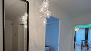 A hallway with a large mirror, a hanging light fixture, and wooden flooring. - Modern apartment - Railway station - City center (Le Mans)