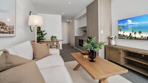 A modern living room with a sofa, a coffee table, and a dining area. - Bright & Cosy Studio in Prime Fremantle Location (Perth)