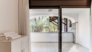 A modern room with a sliding glass door leading to a balcony with a stone wall and greenery. - Florida Ascona Rooms (Ascona)