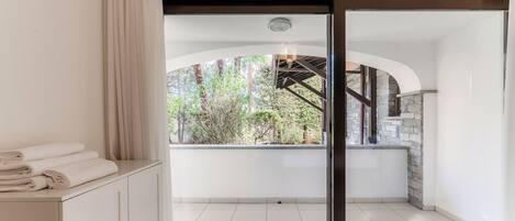 Una habitación moderna con un cerramiento de vidrio corredero que da a un balcón con pared de piedra y vegetación.