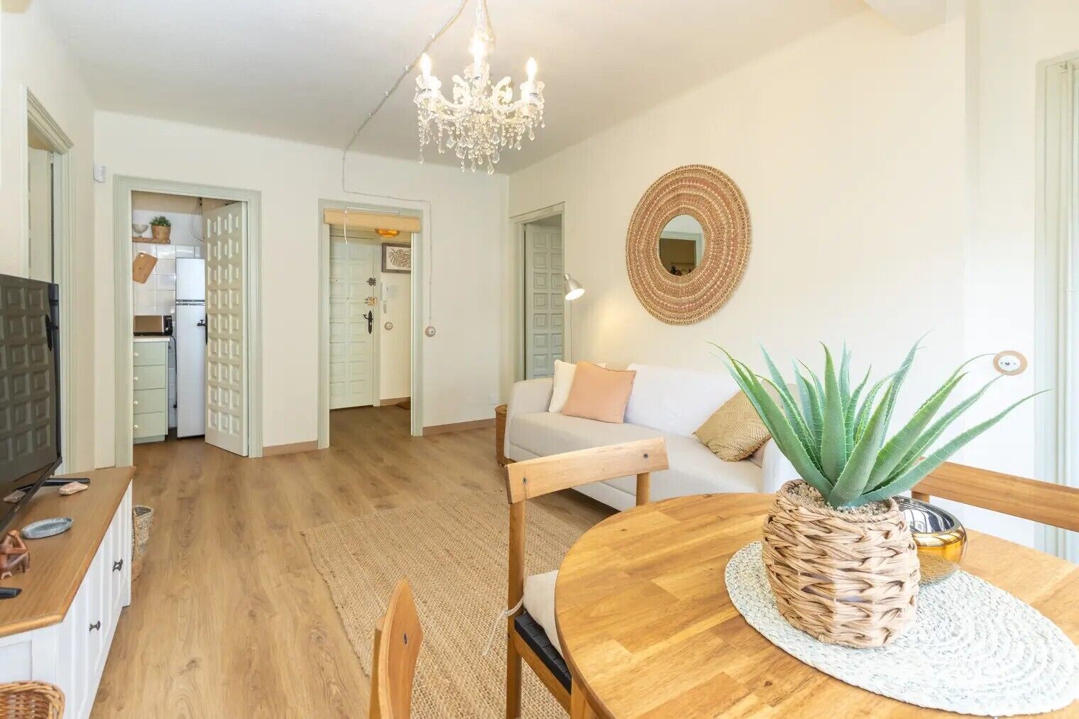 Ein modernes Wohnzimmer mit Esstisch aus Holz, einer Couch und einer Deckenleuchte.