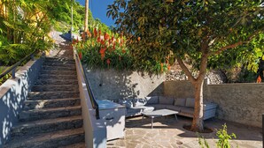 A stone staircase leading to a rooftop patio with outdoor furniture and a tree. - Casa Laranja by HR Madeira (Tabua)