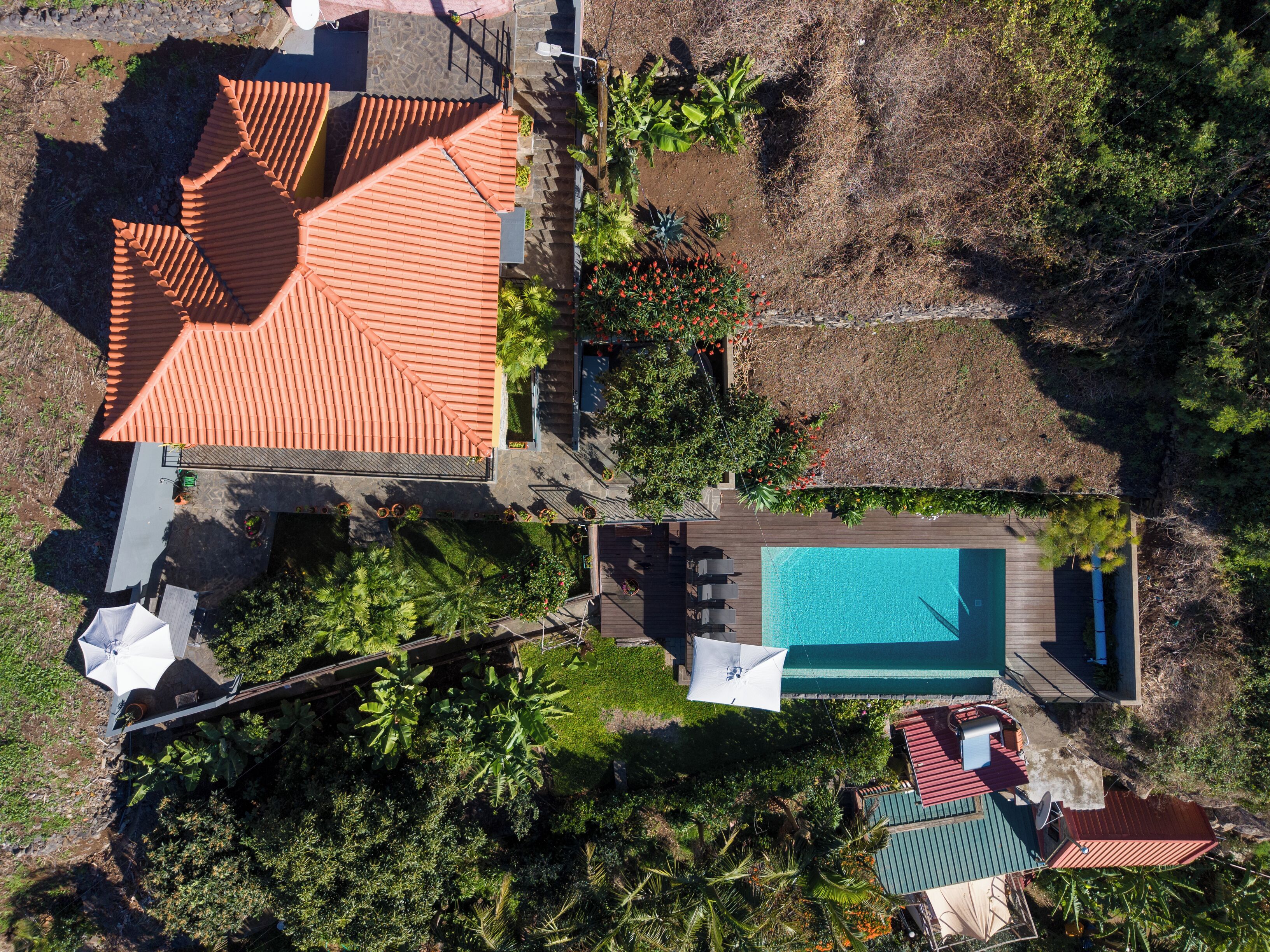 Vista aerea di una proprietà con piscina, zona patio e un edificio con tetto rosso.