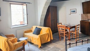Ein gemütliches Zimmer mit Esstisch, Stühlen, einer Couch und einem Fenster.