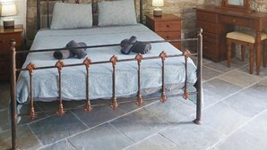 Ein Schlafzimmer mit Stewand, einem Bett mit Metallgestell, einer Holzkommode und einem Spiegel.