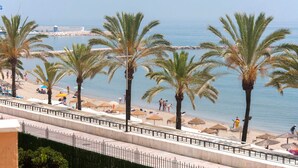 Une plage avec des palmiers, des parasols et des gens.
