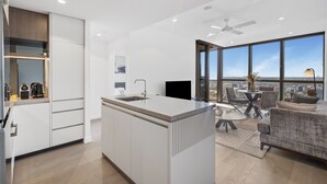 A modern kitchen with a central island, a dining area with a table and chairs, and a sofa. - Stylish 1-bed Apartment in Brisbane CBD (Brisbane)