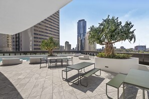 Eine Dachterrasse mit Außenmöbeln, einem Pool und Blick auf die Skyline der Stadt.