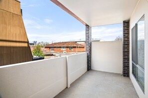 A balcony with a view of a brick building and a cityscape. - Bright 2-bed Flat With Balcony in Kensington (Melbourne)